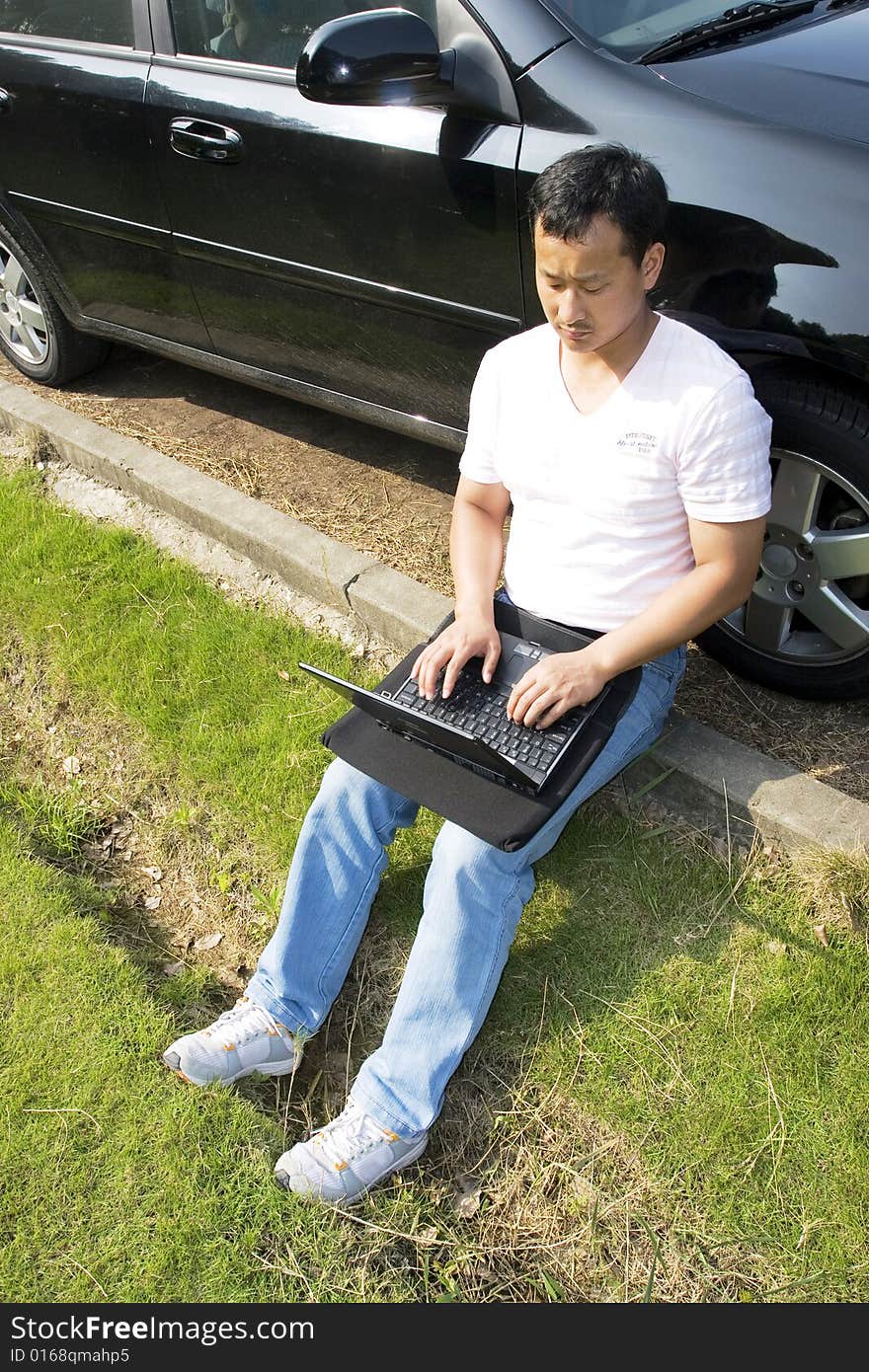 The man working outdoors with a laptop.