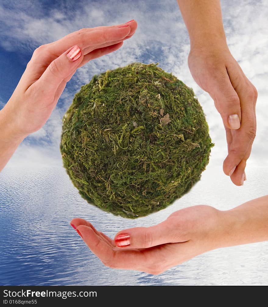 Recycling symbol made from hands; cloudy blue sky and ocean as a background