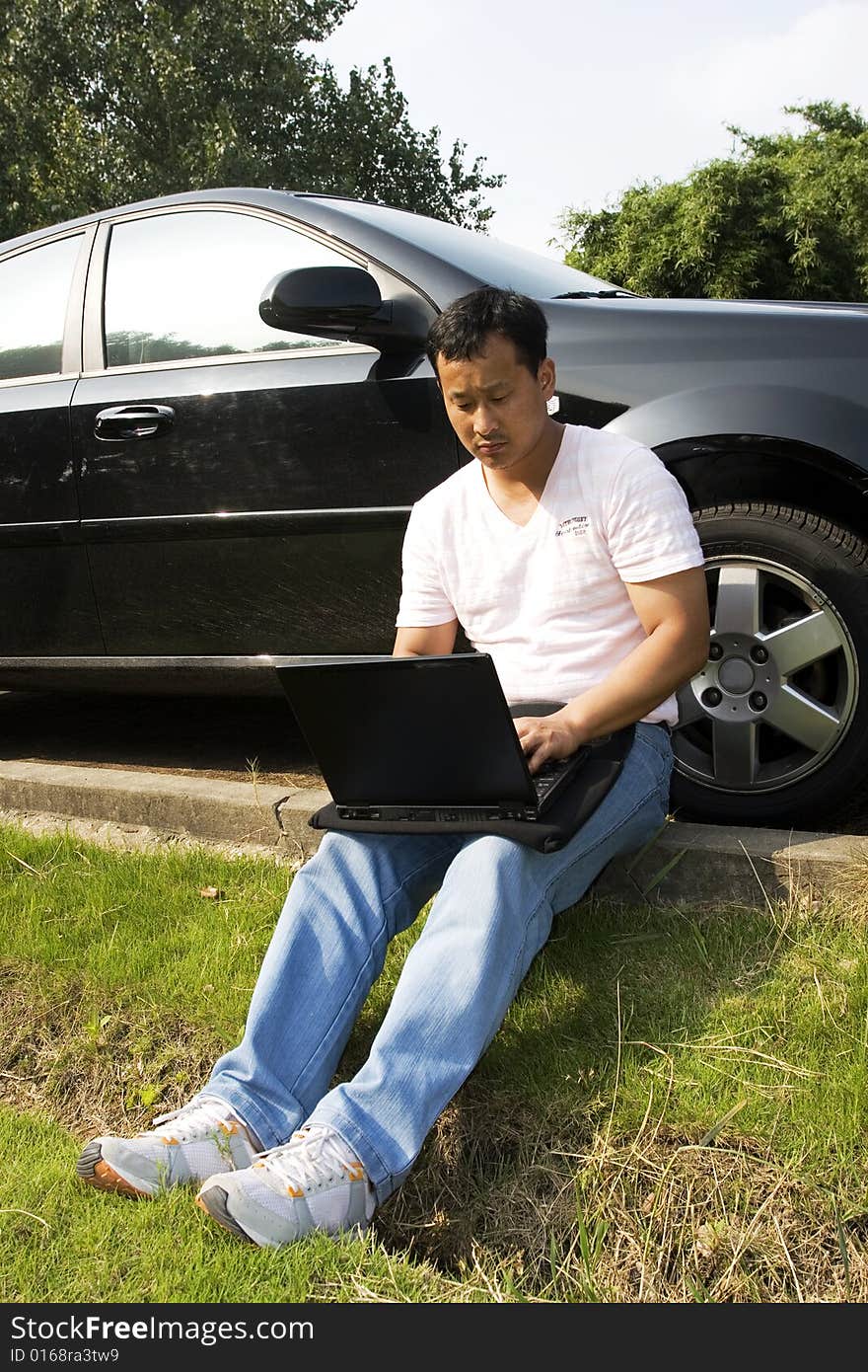 The man working outdoors with a laptop.