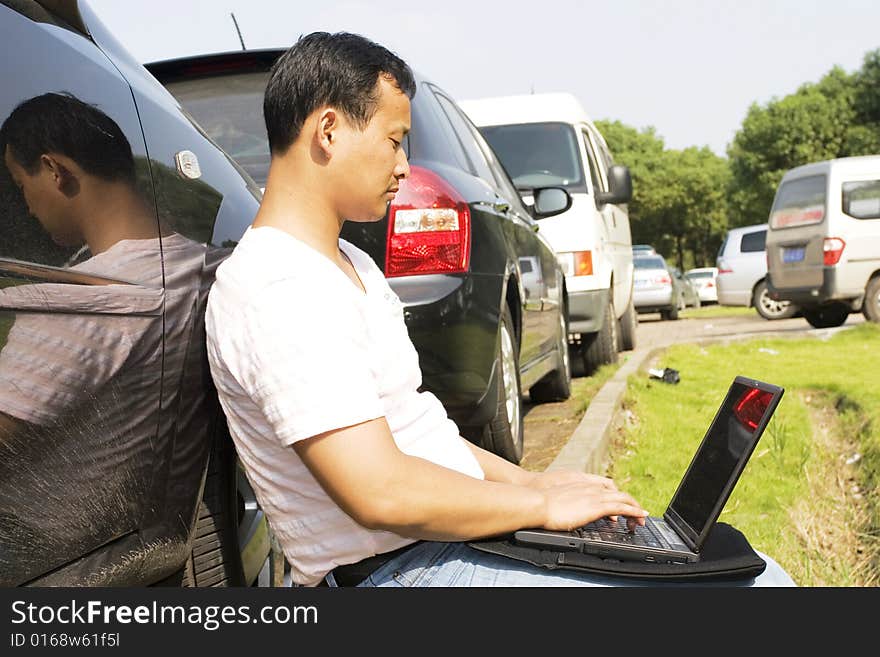 The man working outdoors with a laptop.