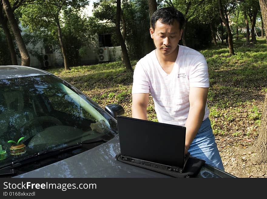 The man working outdoors with a laptop.