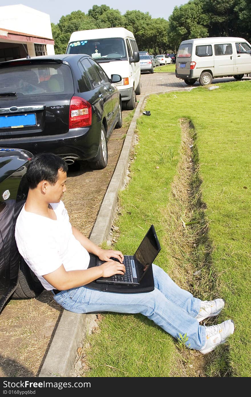 The man working outdoors with a laptop.