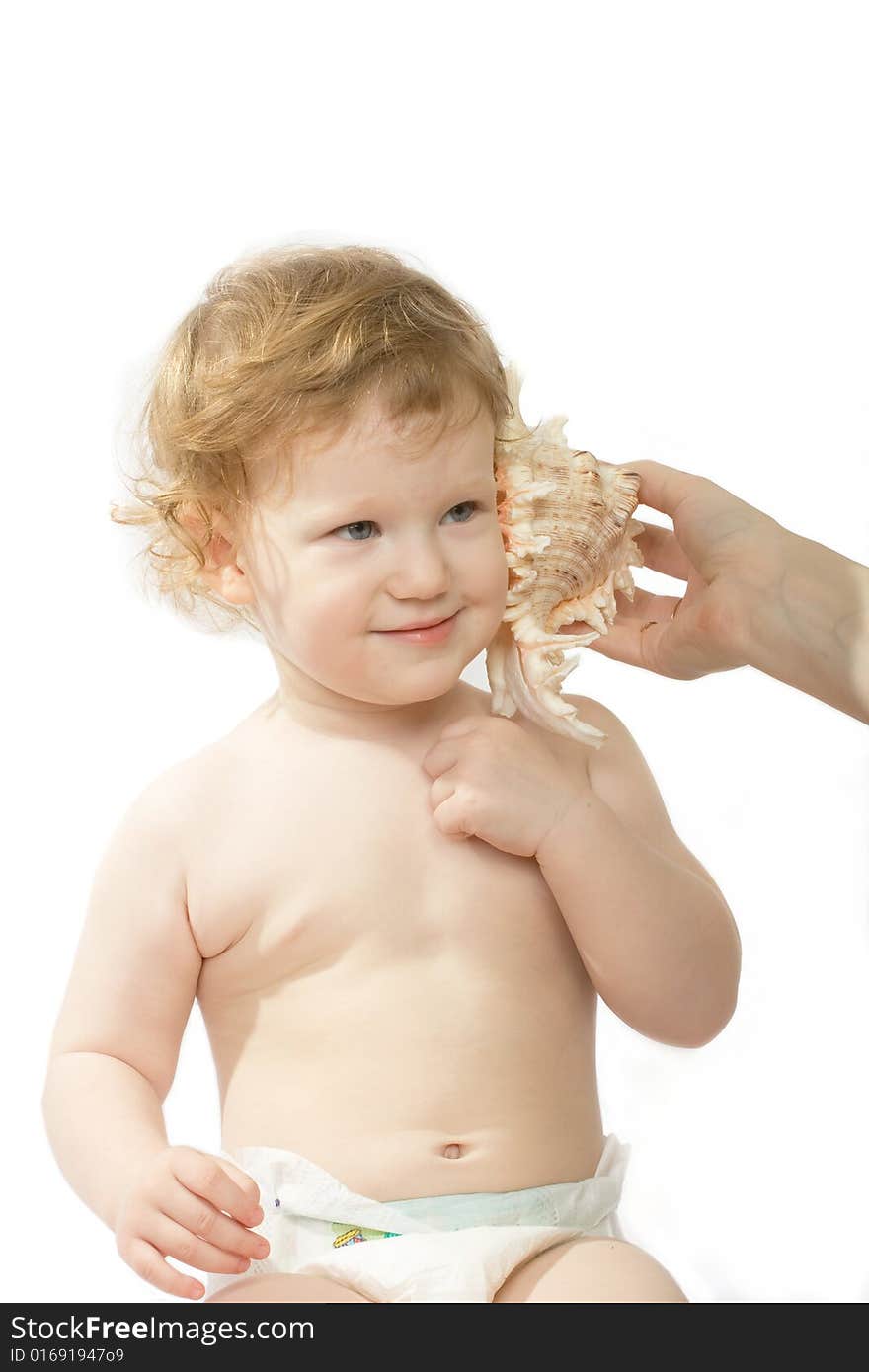 A baby listens to a sea noise in the sea shell. A baby listens to a sea noise in the sea shell