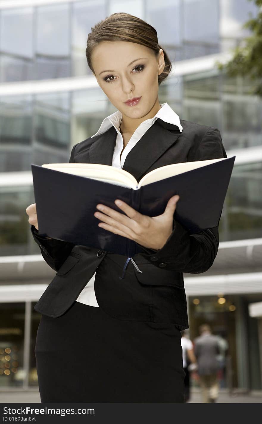 Young brunette businesswoman outdoors with a notebook. Young brunette businesswoman outdoors with a notebook