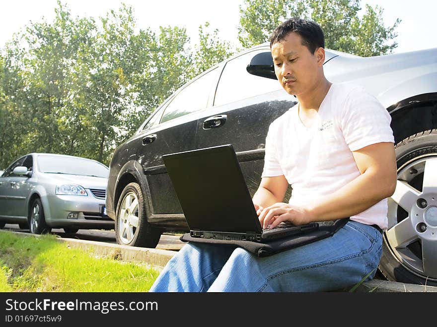 The man working outdoors with a laptop.