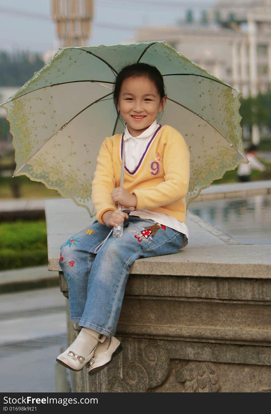 The smiling girl with a umbrella in a park .