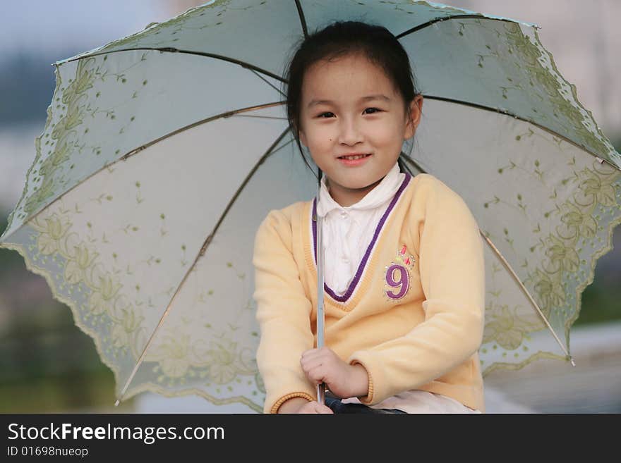 The smiling girl with a umbrella in a park .