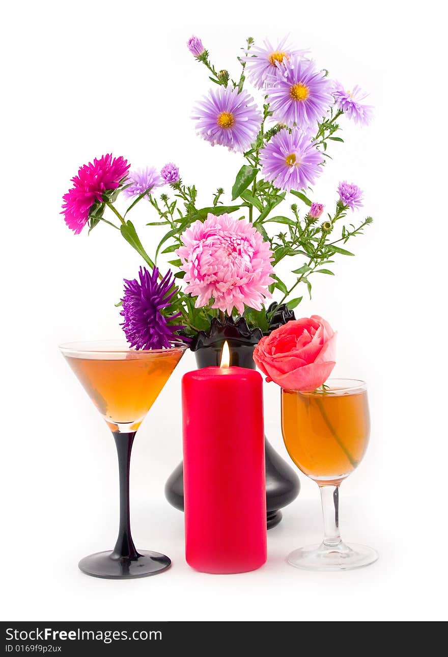 Black vase with colors and burning red candle with scarlet rose at wine-glass with wine on white background