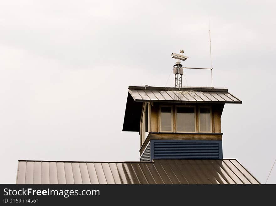 A metal roof on a seaside building with a video camera on top. A metal roof on a seaside building with a video camera on top