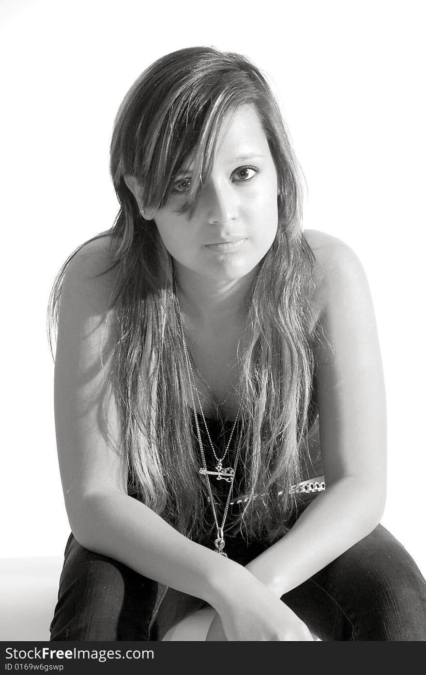 Attractive young lady sitting in front of a white background. Attractive young lady sitting in front of a white background