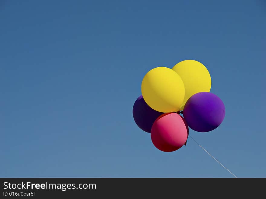 Group of colorful helium inflated balloons floating in clear blue sky with copyspace. Group of colorful helium inflated balloons floating in clear blue sky with copyspace