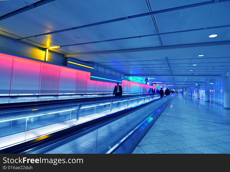 People moving in glass corridor in blue. People moving in glass corridor in blue