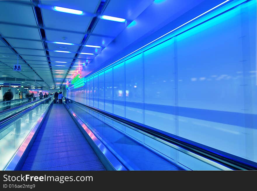 People moving in glass corridor in blue. People moving in glass corridor in blue