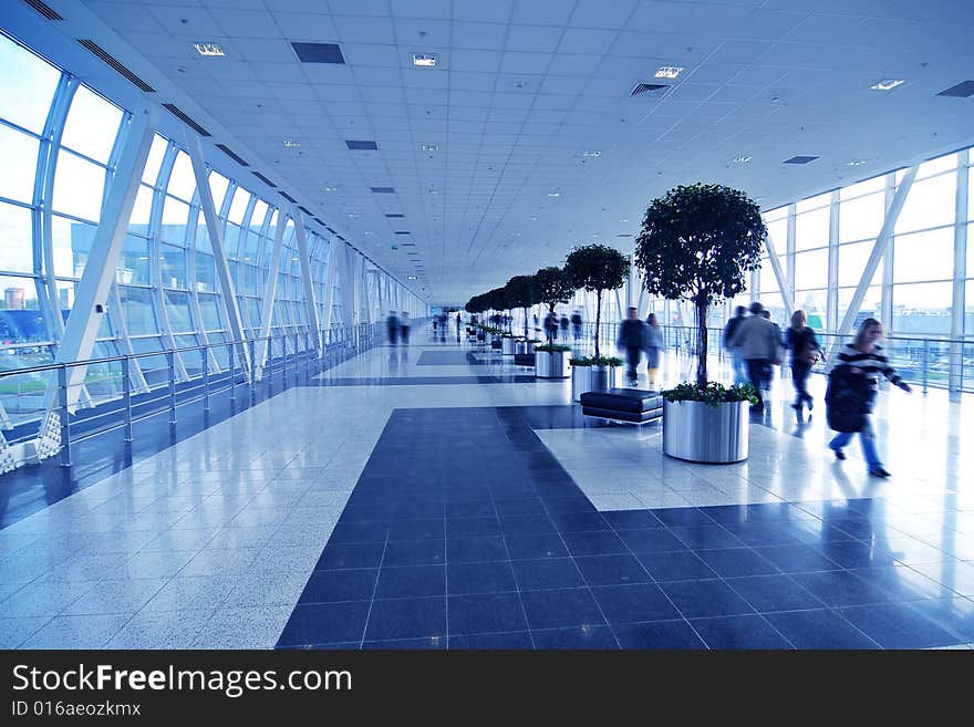 People moving in glass corridor in blue