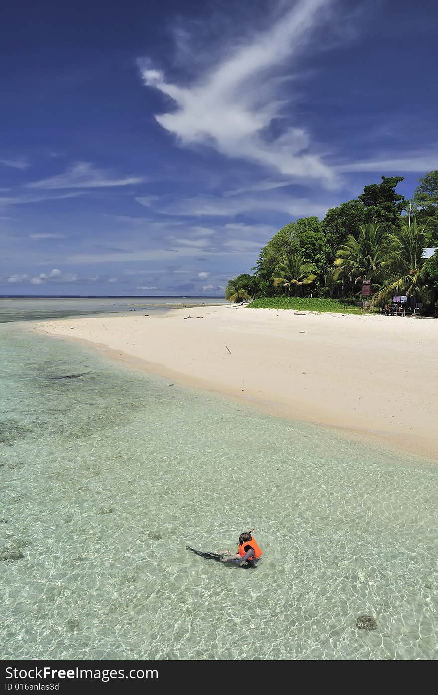 A guy in a red life jacket snorkeling on a tropical beach in Malaysia. A guy in a red life jacket snorkeling on a tropical beach in Malaysia