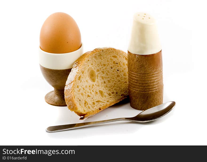 A soft boiled egg, a slice of bread and a saltpot