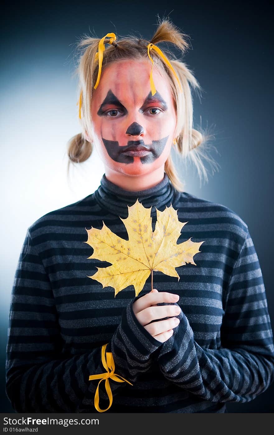 Jack-o-lantern girl with autumn leaves isolated in studio