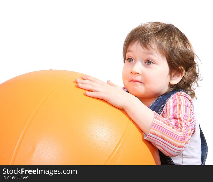 Little girl playing with big orange ball on white ground