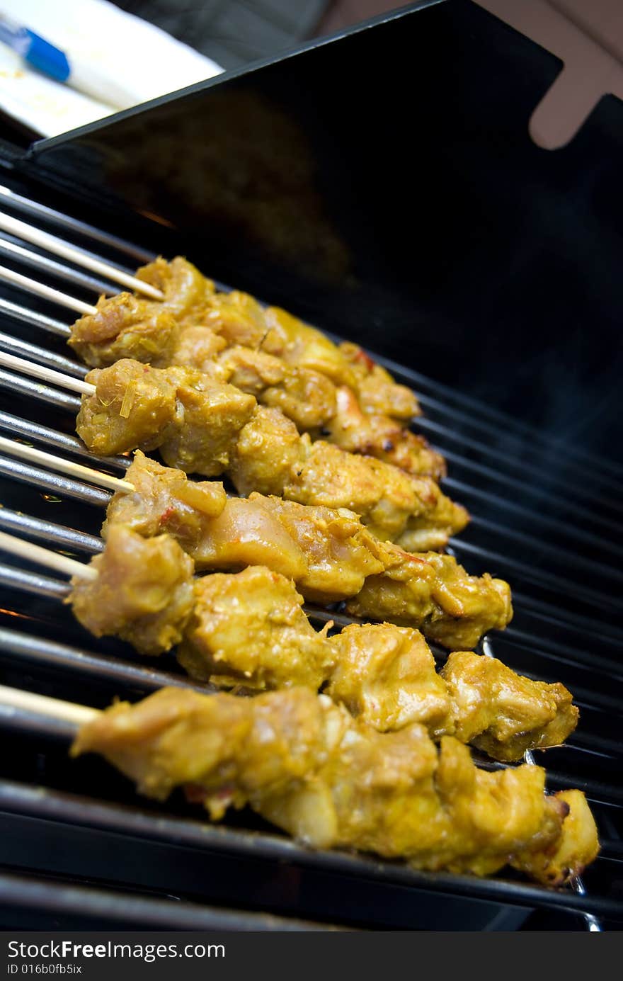 Barbequeing malaysian style chicken on a skewer -- satays. Barbequeing malaysian style chicken on a skewer -- satays.