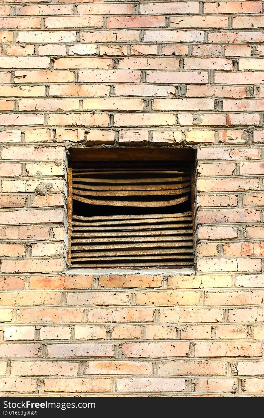 Old metal rusty ventilation window on brick wall.