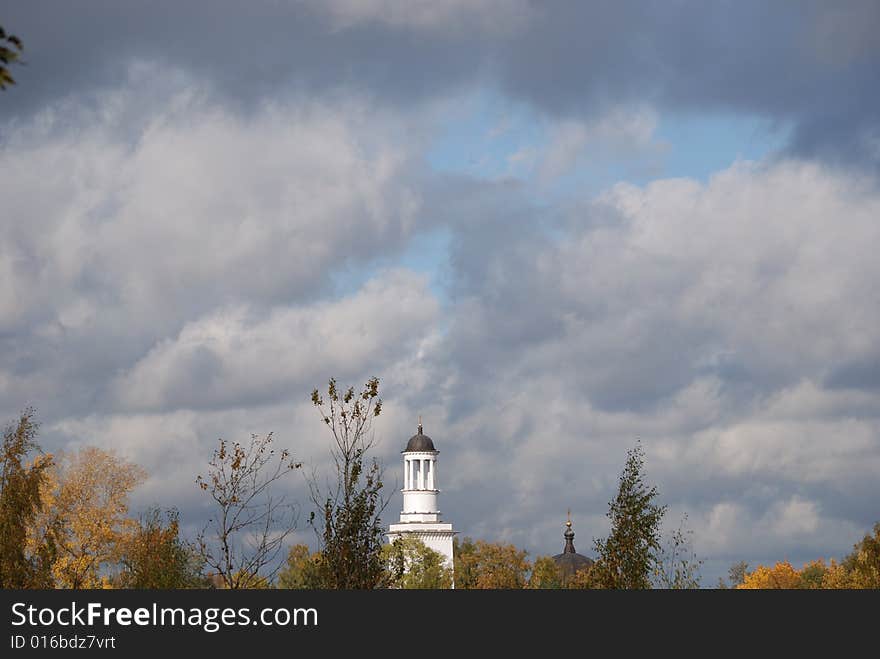 White church, could be seen after trees with an autumn foliage