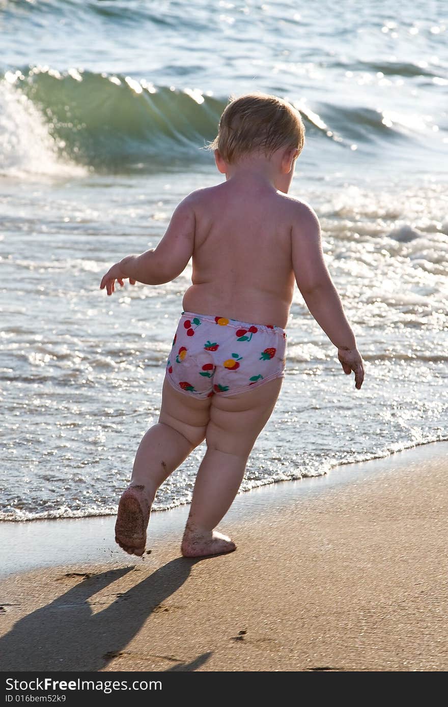 Child runs on a beach on a background of waves