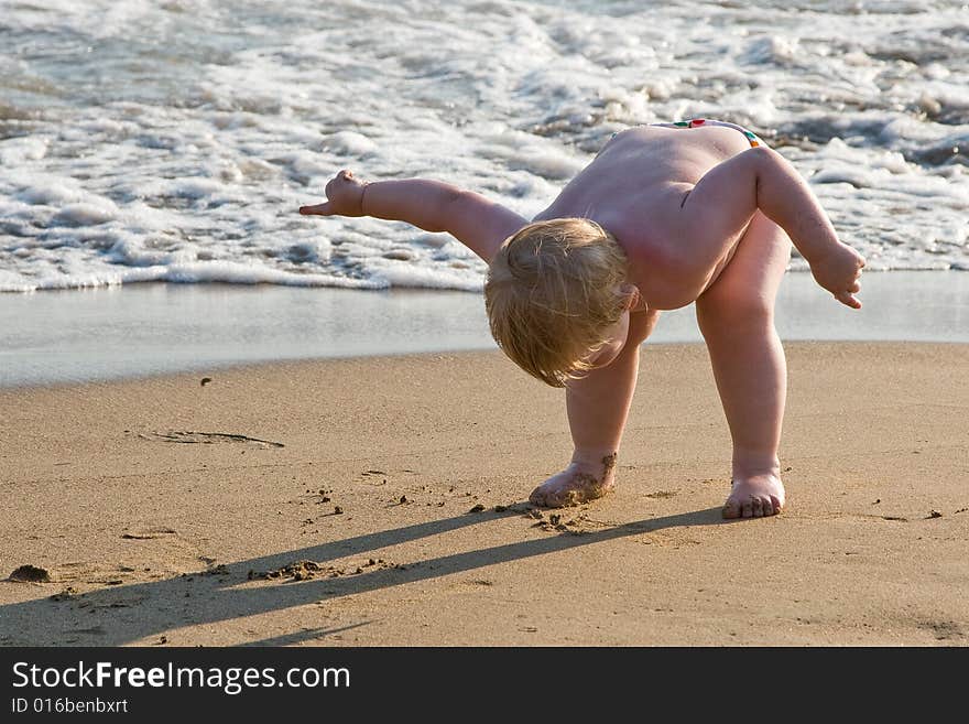 Small child stands having bent down on a beach. Small child stands having bent down on a beach