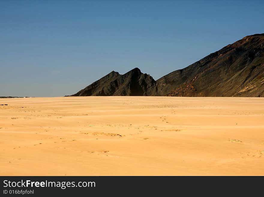 Isolated beach with footprints and cliffs on diagonal