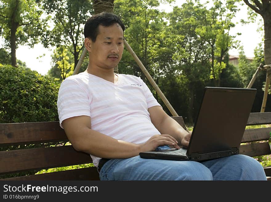 A young man using a laptop in the park