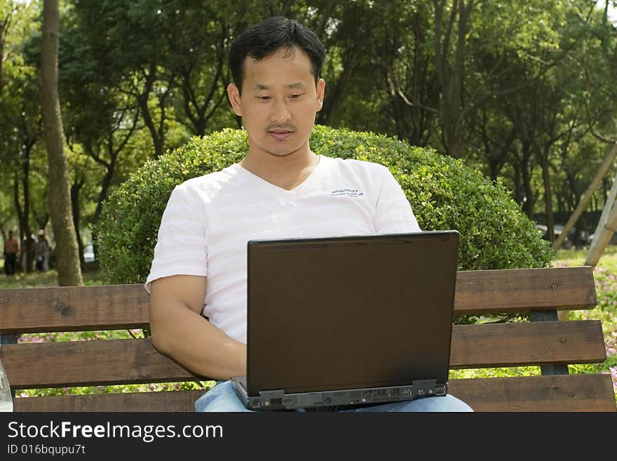 A young man using a laptop in the park