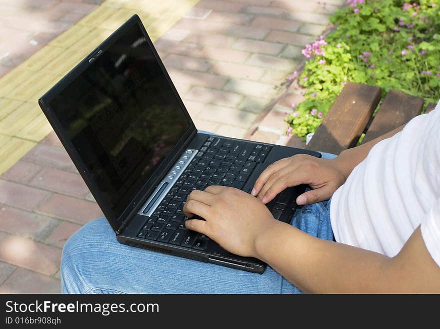 A young man using a laptop in the park