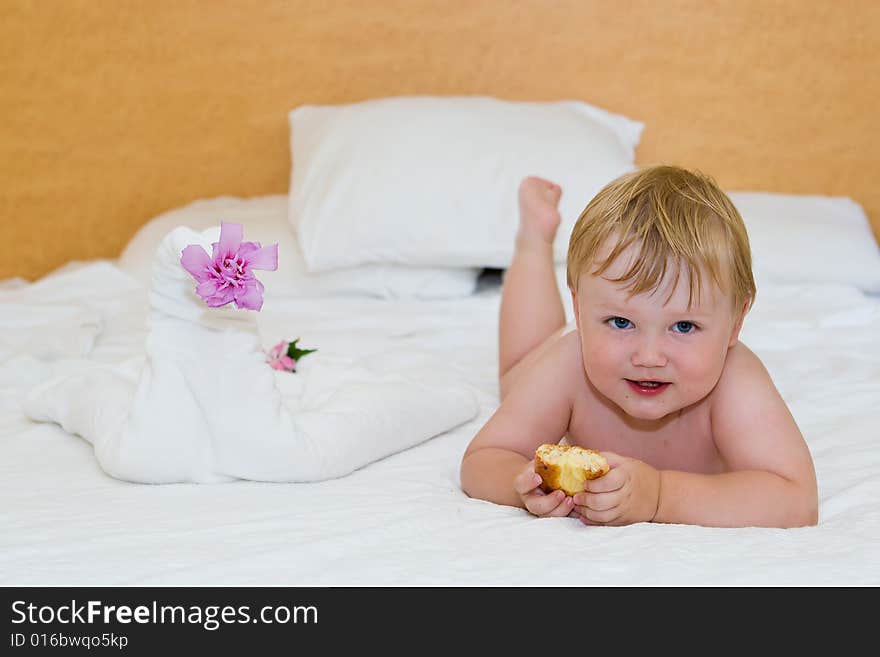 Small child with a cake lays on a bed. Small child with a cake lays on a bed