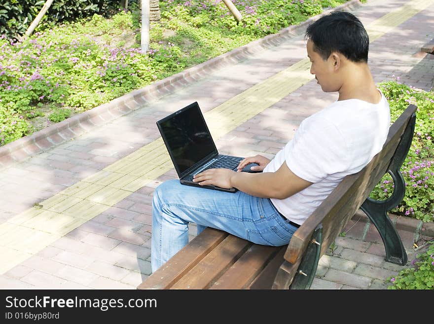 A young man using a laptop in the park