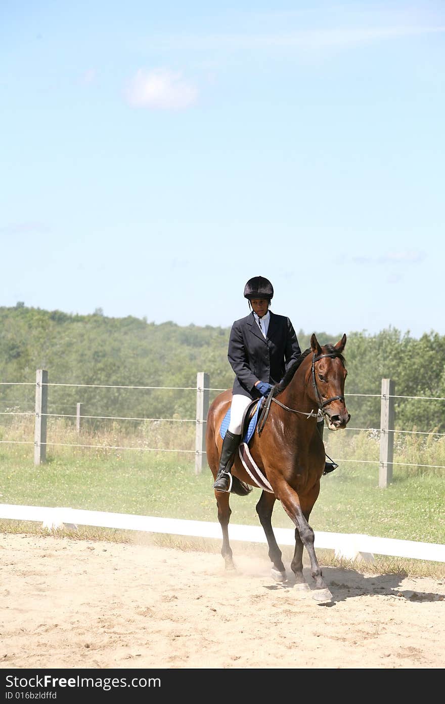 African American teenage girl riding a brown horse with dust from the ground. African American teenage girl riding a brown horse with dust from the ground