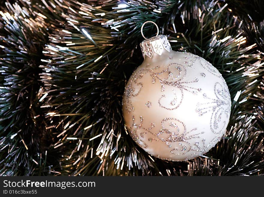 White Christmas bauble in green tinsel. White Christmas bauble in green tinsel