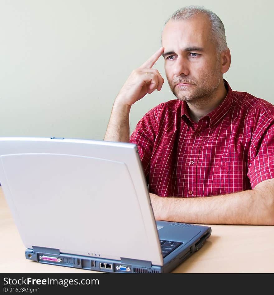 Thoughtful office worker working at the desk with laptop