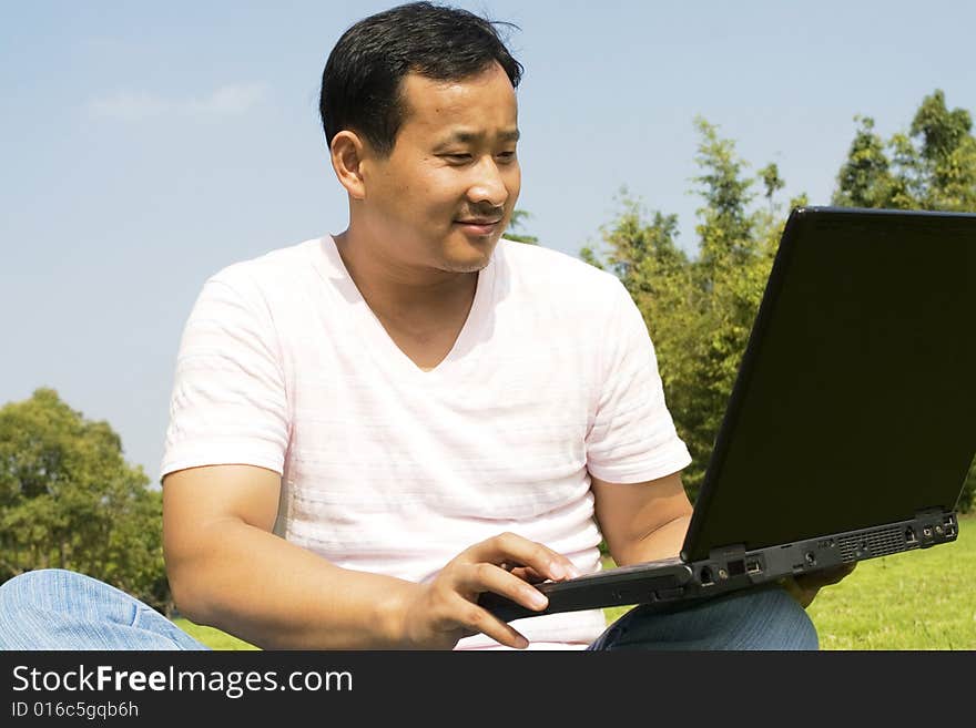 A young man using a laptop outdoors. A young man using a laptop outdoors