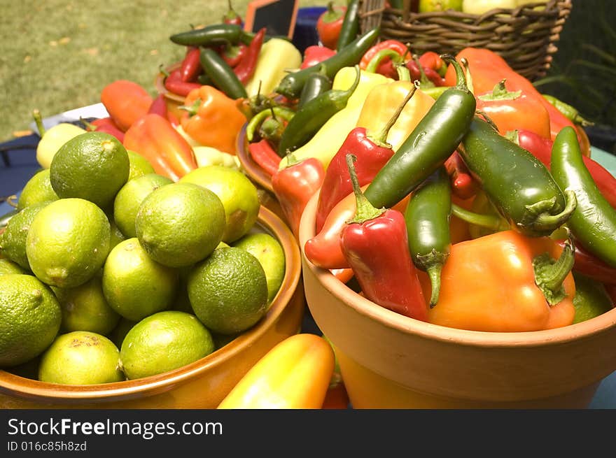 Bowl of freshly picked limes and peppers in a farmers market. Bowl of freshly picked limes and peppers in a farmers market