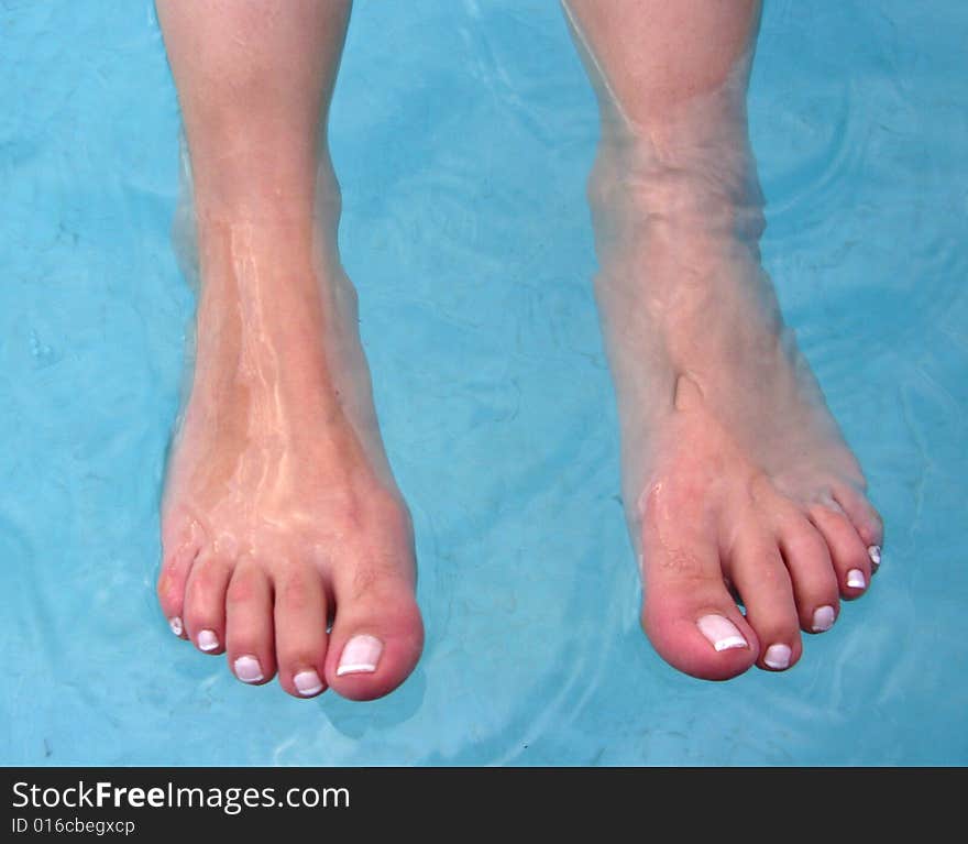 Relaxing in the pool - feet of swimming woman