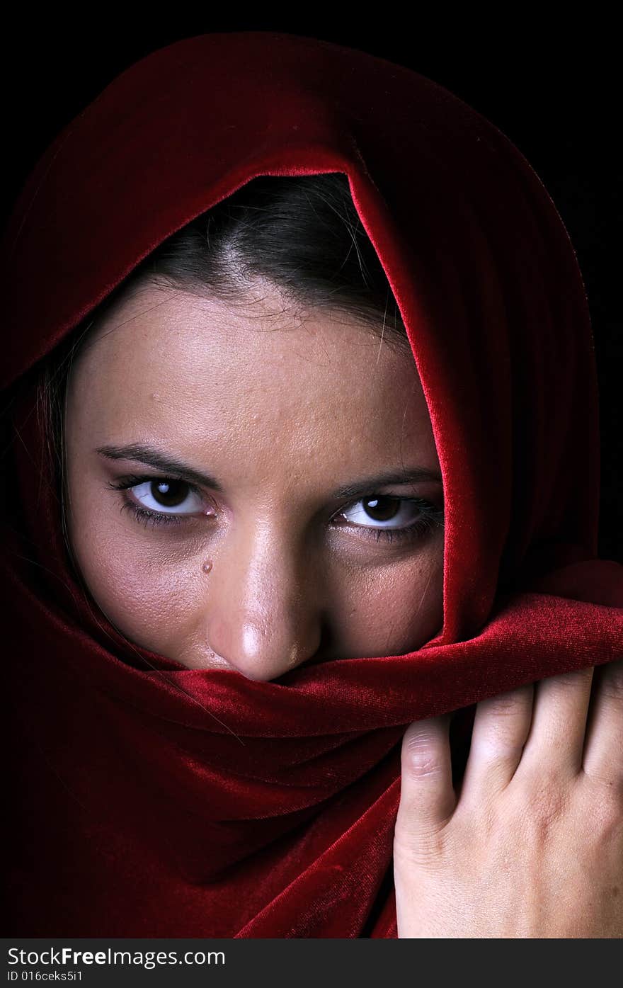 Beautiful young brunette woman in closeup with red shawl over face. Beautiful young brunette woman in closeup with red shawl over face