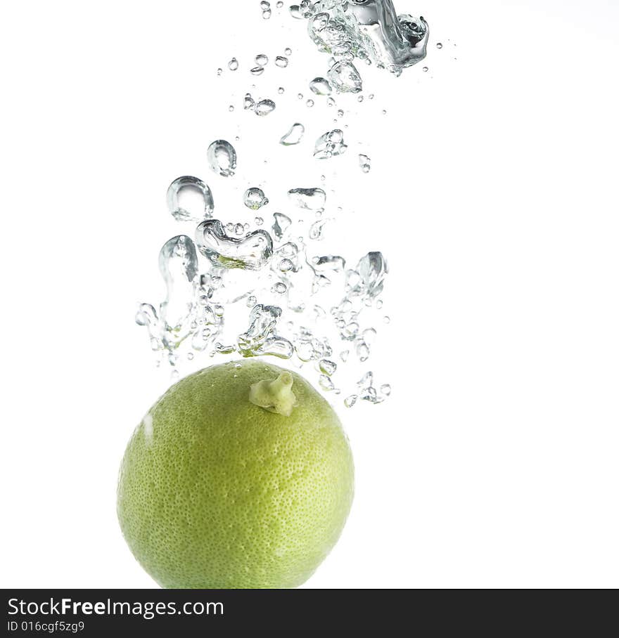 Single green lime pouring in water with  bubbles train. Single green lime pouring in water with  bubbles train