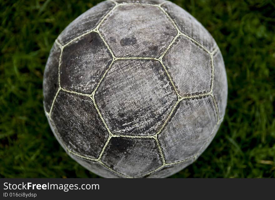 One grey old football on the grass outside. taken close up and on top of the ball.