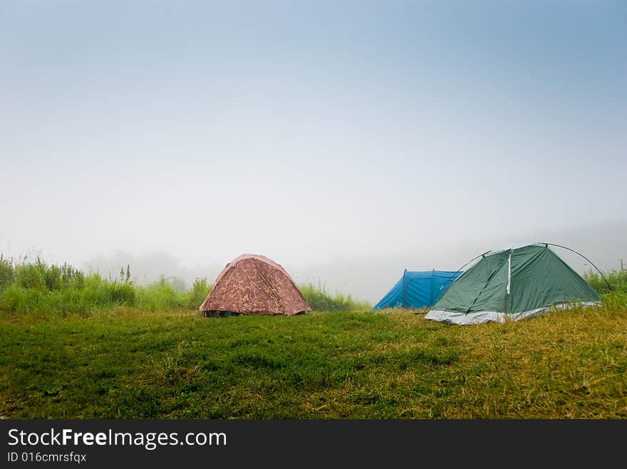 Tourist tents on a grass in a fog