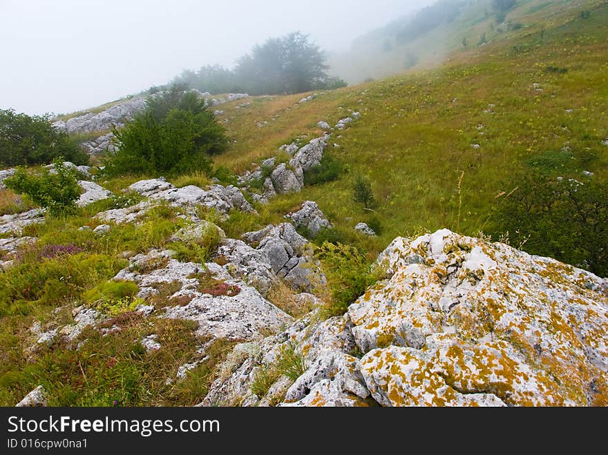 Misty morning meadow in Crimea mountains, Ukraine. Stones on a foreground