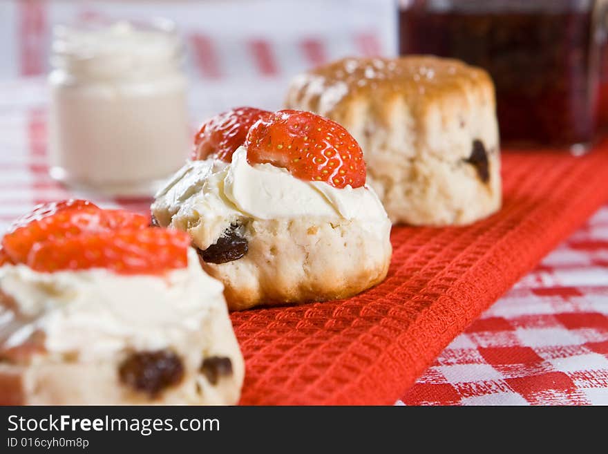 A line of scone halves with strawberrie and cream