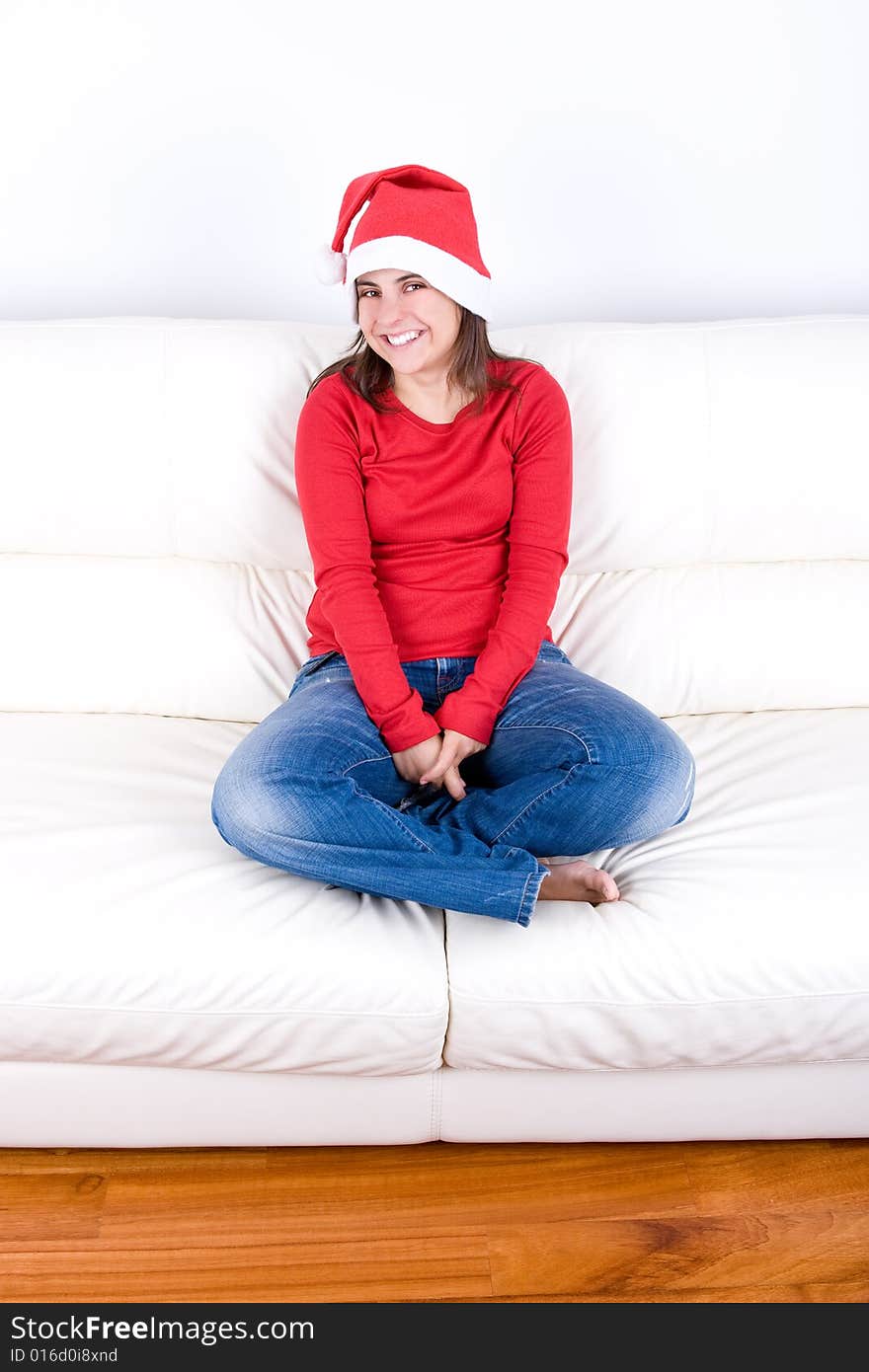 Beautiful young woman with red christmas hat sitting in home sofa. Beautiful young woman with red christmas hat sitting in home sofa