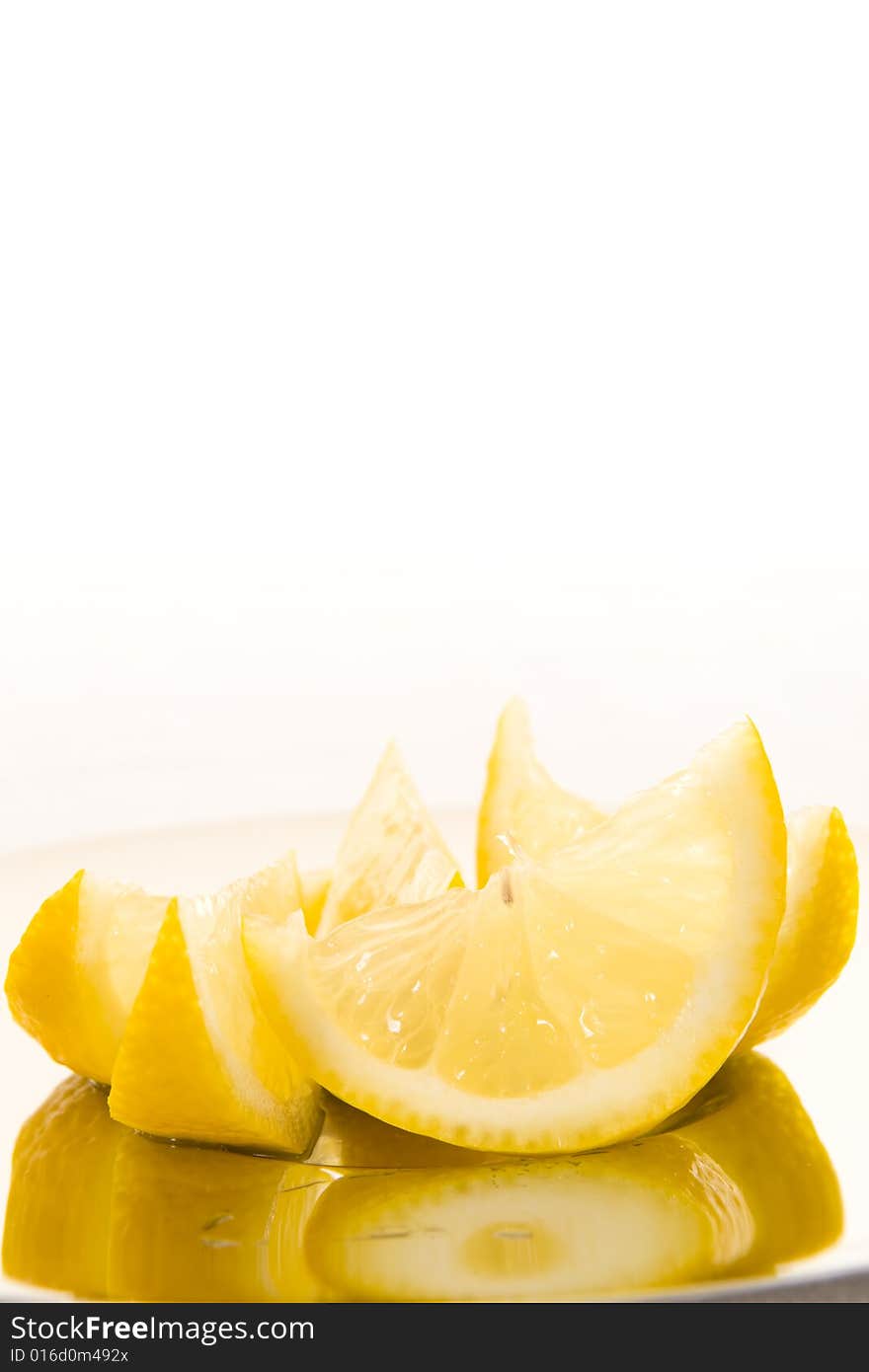 Freshly cut slices of lemon on a shiny plate with a white background. Copy space. Freshly cut slices of lemon on a shiny plate with a white background. Copy space.