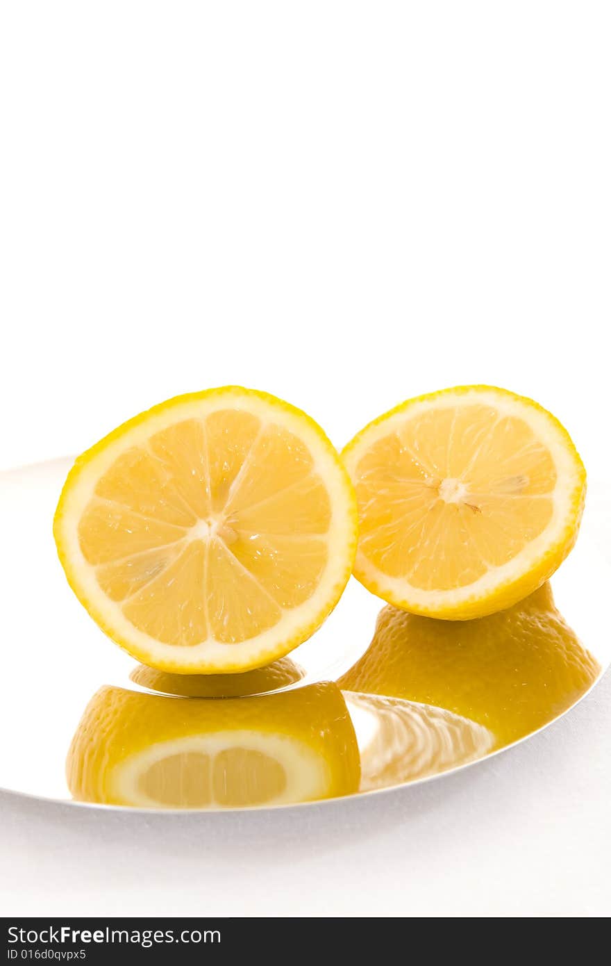 Freshly cut slices of lemon on a shiny plate with a white background. Copy space. Freshly cut slices of lemon on a shiny plate with a white background. Copy space.