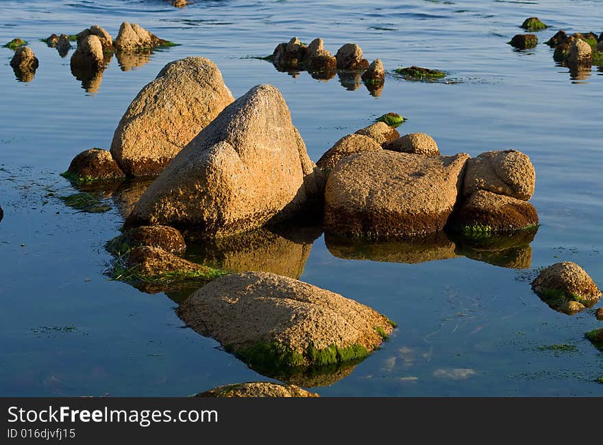 A close-up of the brown-red stones in seawater. Summer, early evening. A close-up of the brown-red stones in seawater. Summer, early evening.