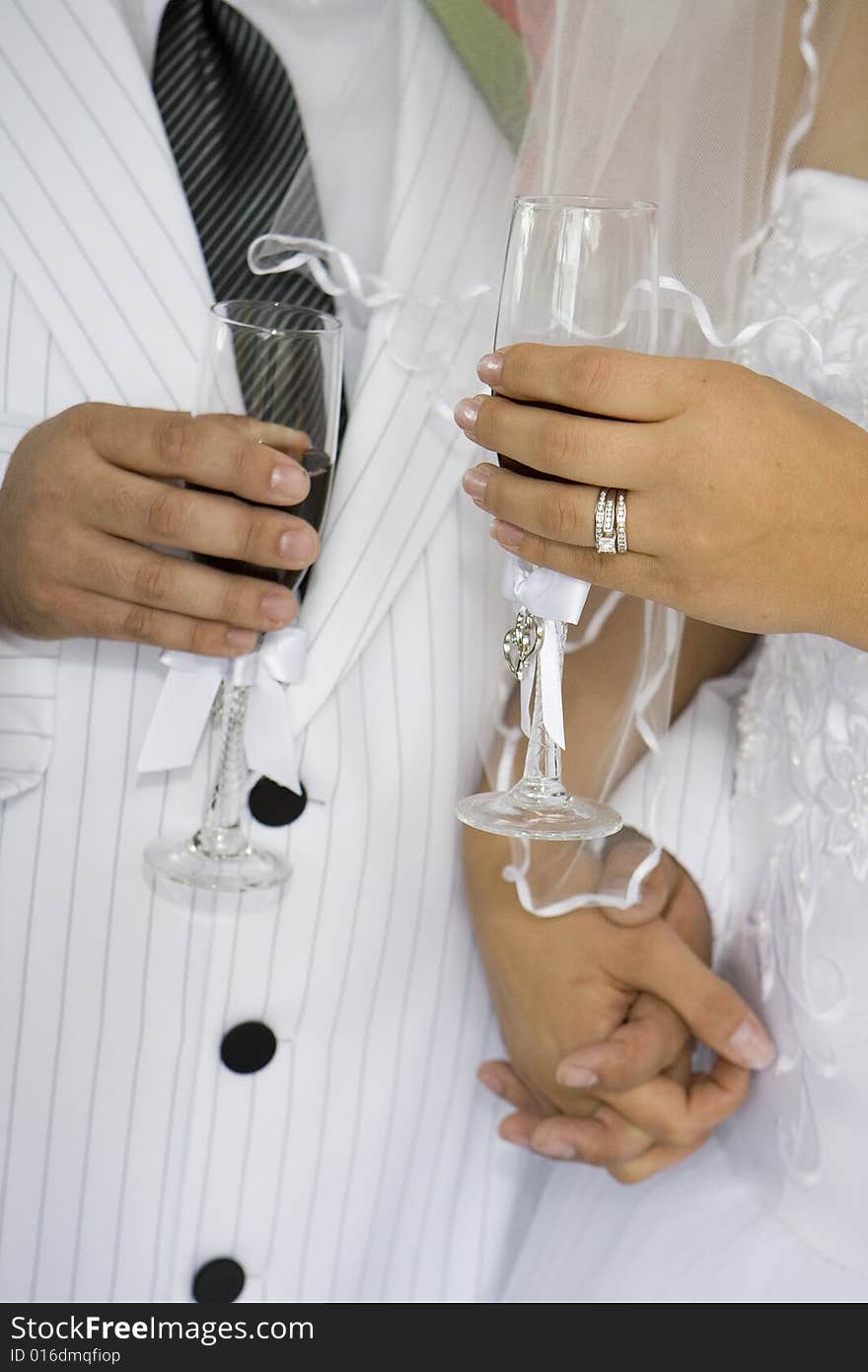 Torso of a bride and groom with bride's ring visible sharing a toast. Torso of a bride and groom with bride's ring visible sharing a toast.